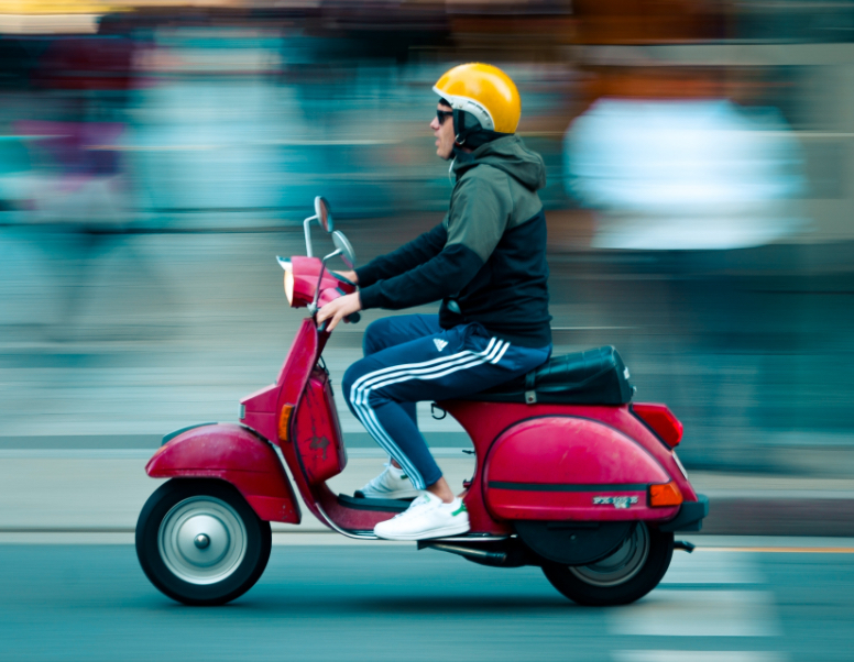 Auto theorie oefenen, man op een rode scooter met een gele helm