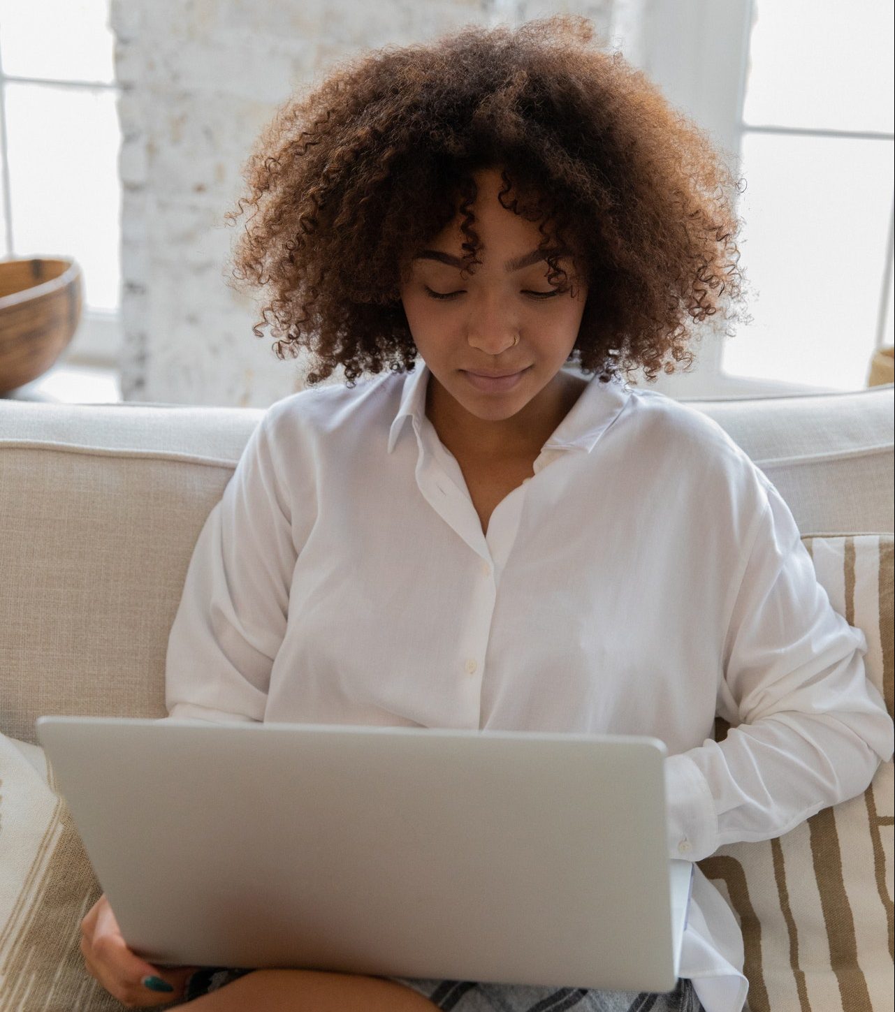 Online auto theorie, vrouw zit op een bank en werkt op haar laptop